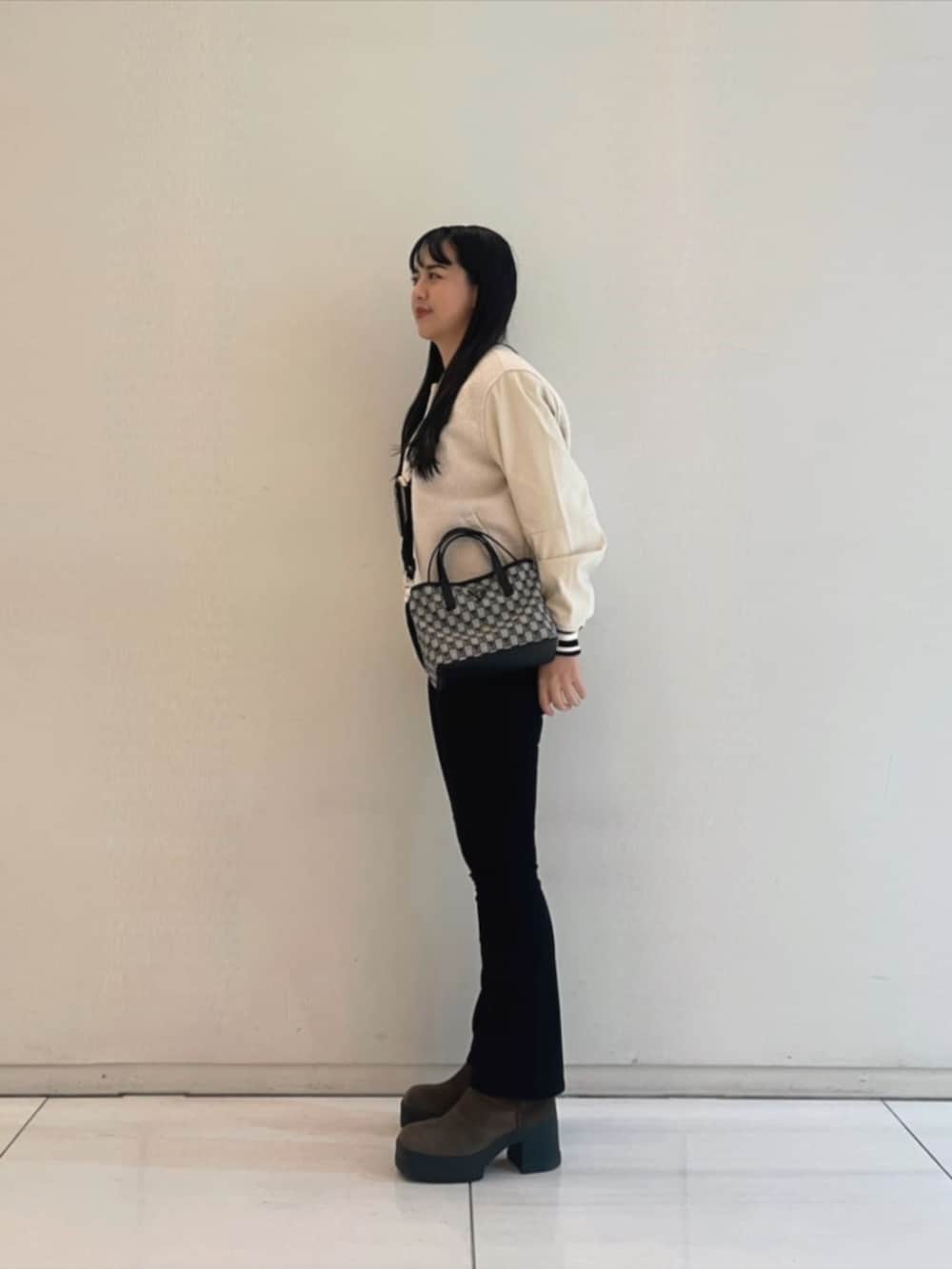 ブラック系のデニムパンツ、ブラック系のショルダーバッグ、ホワイト系のニット/セーターを着用したレディースの秋コーディネートの3枚目の写真