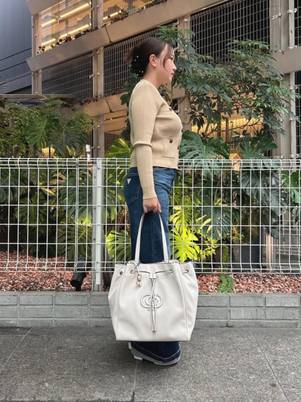 ベージュ系のカーディガン/ボレロ、ブルー系のデニムパンツ、ホワイト系のトートバッグを着用したレディースの秋コーディネートの3枚目の写真