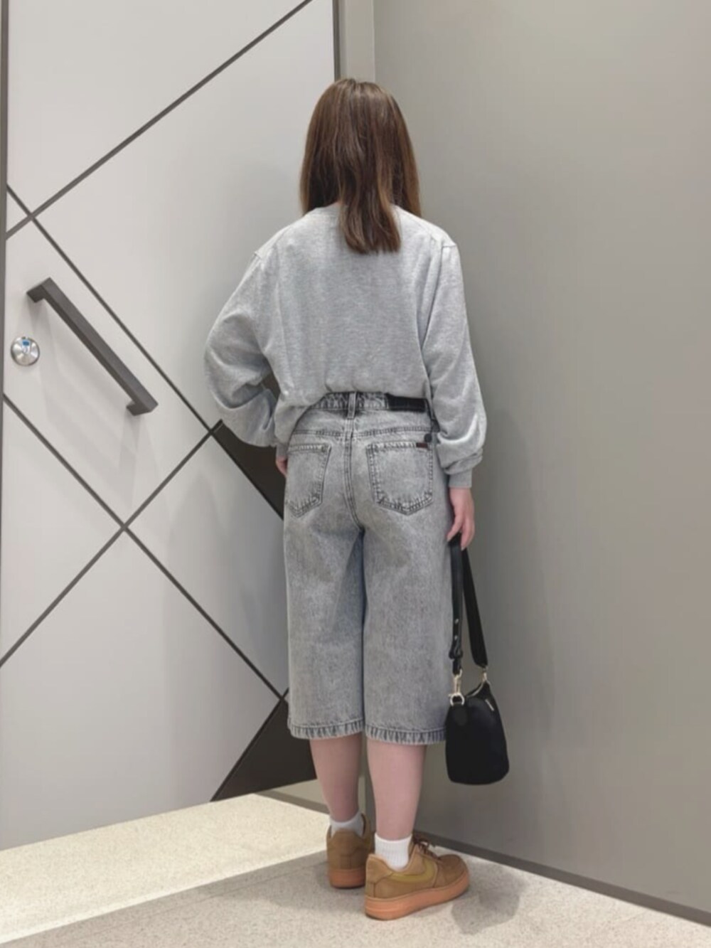 ブラック系のハンドバッグ、グレー系のデニムパンツ、グレー系のニット/セーターを着用したレディースの夏コーディネートの2枚目の写真