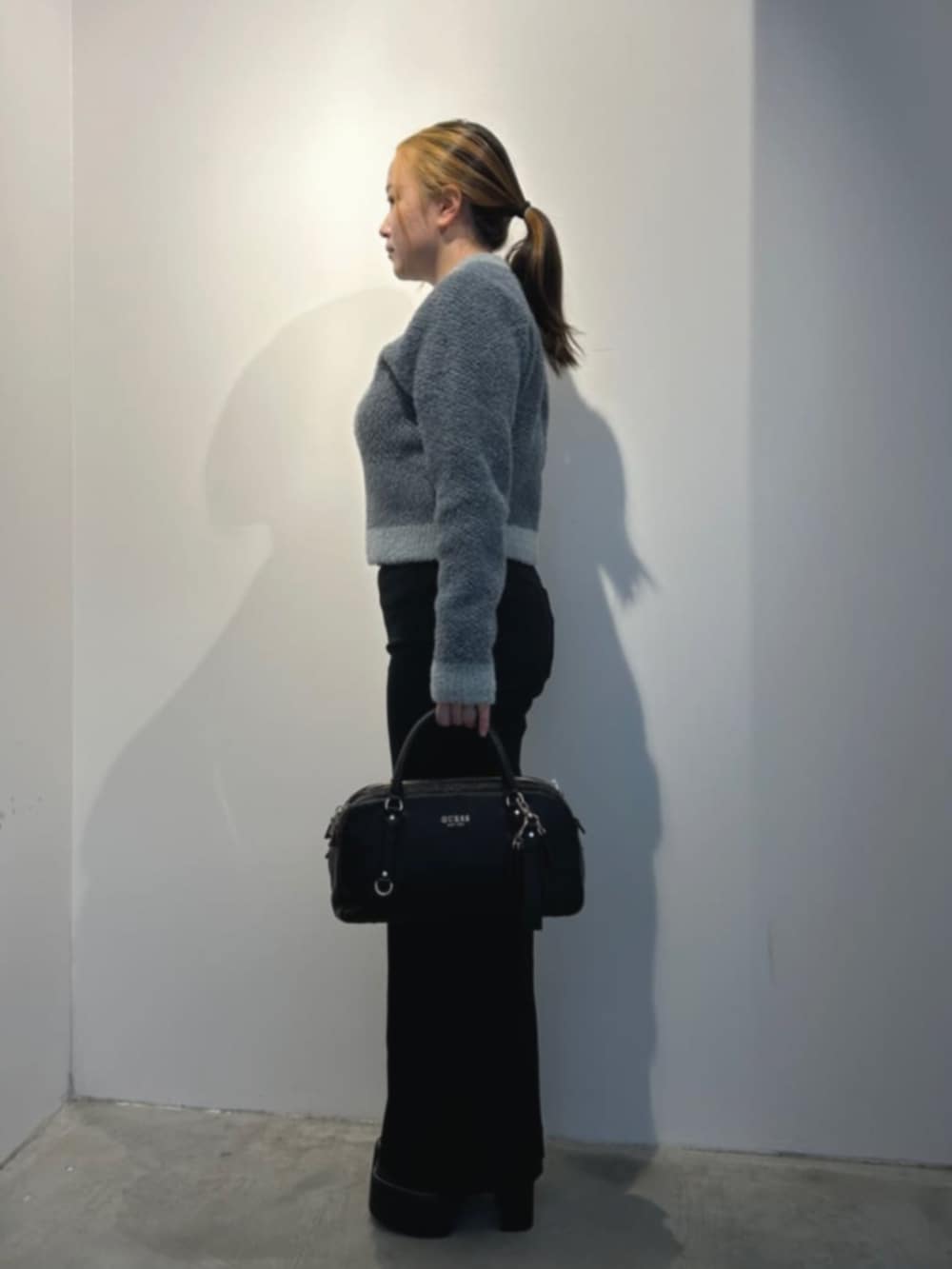 ブラック系のデニムパンツ、グレー系のニット/セーター、ブラック系のショルダーバッグを着用したレディースの冬コーディネートの3枚目の写真