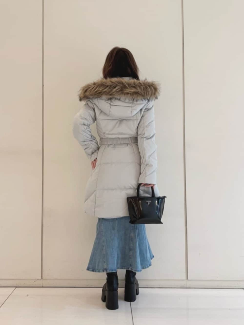 グレー系のダウンジャケット/コート、ブルー系のデニムスカート、ブラック系のトートバッグを着用したレディースの冬コーディネートの2枚目の写真
