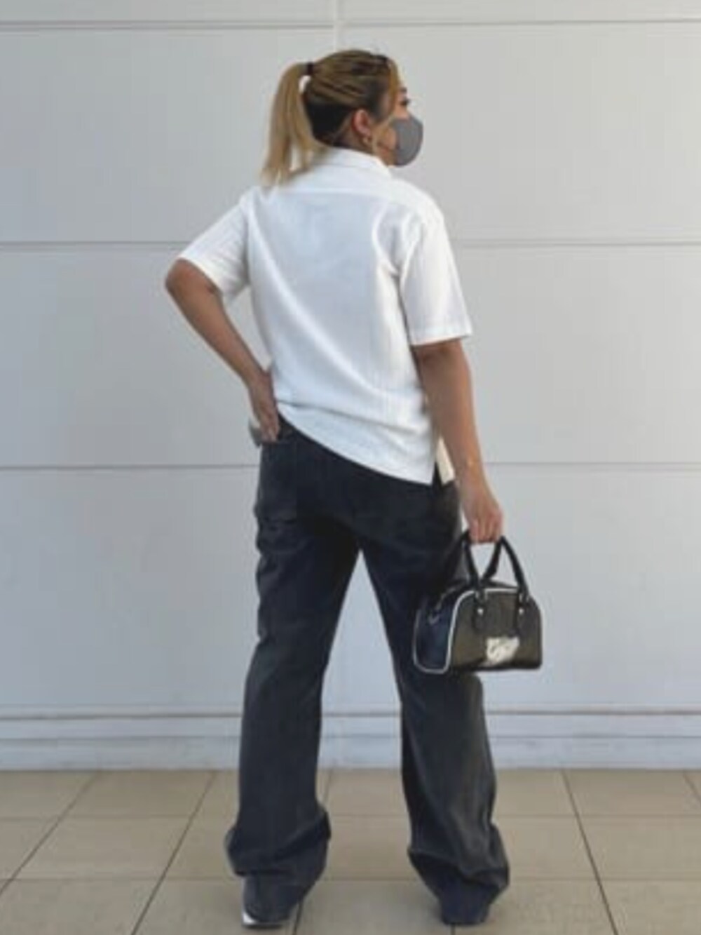 グレー系のデニムパンツ、ブラック系のハンドバッグ、ホワイト系のシャツ/ブラウスを着用したレディースの夏コーディネートの2枚目の写真