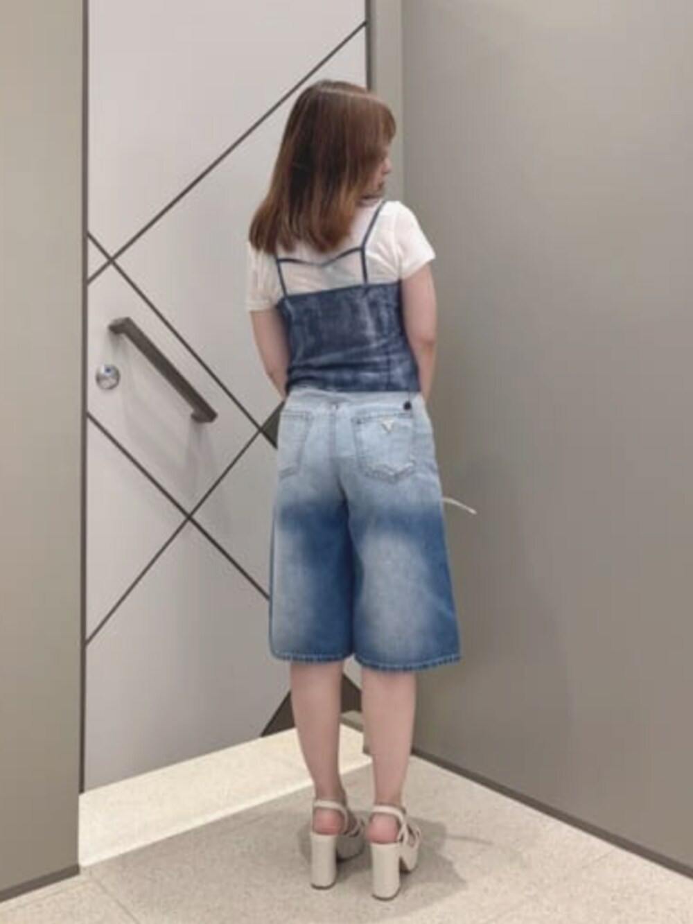 ベージュ系のショルダーバッグ、ホワイト系のその他トップス、ブルー系のデニムパンツを着用したレディースの夏コーディネートの2枚目の写真