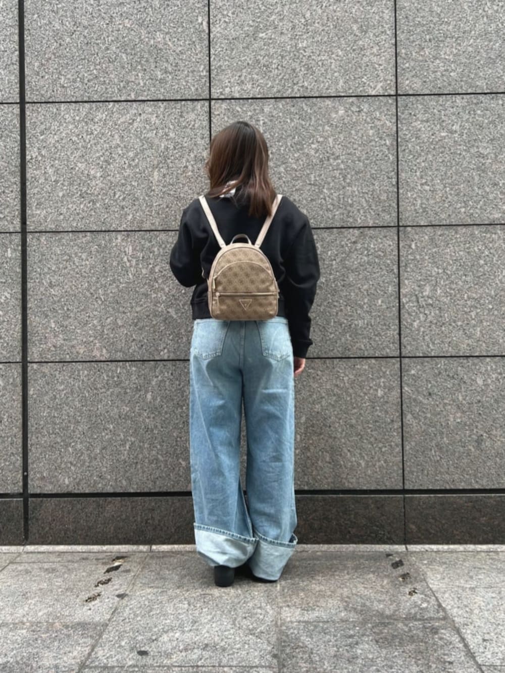 ベージュ系のバックパック/リュック、ブラック系のスウェット、ブルー系のデニムパンツを着用したレディースの冬コーディネートの2枚目の写真