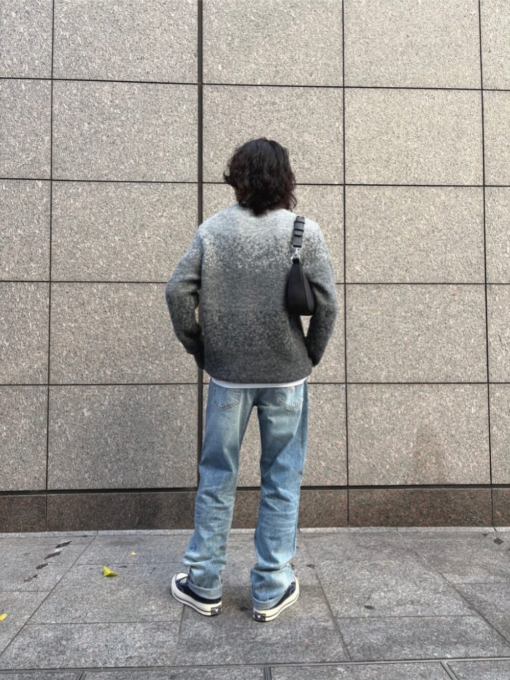 ブルー系のデニムパンツ、ブラック系のショルダーバッグ、グレー系のニット/セーターを着用したメンズの冬コーディネートの2枚目の写真