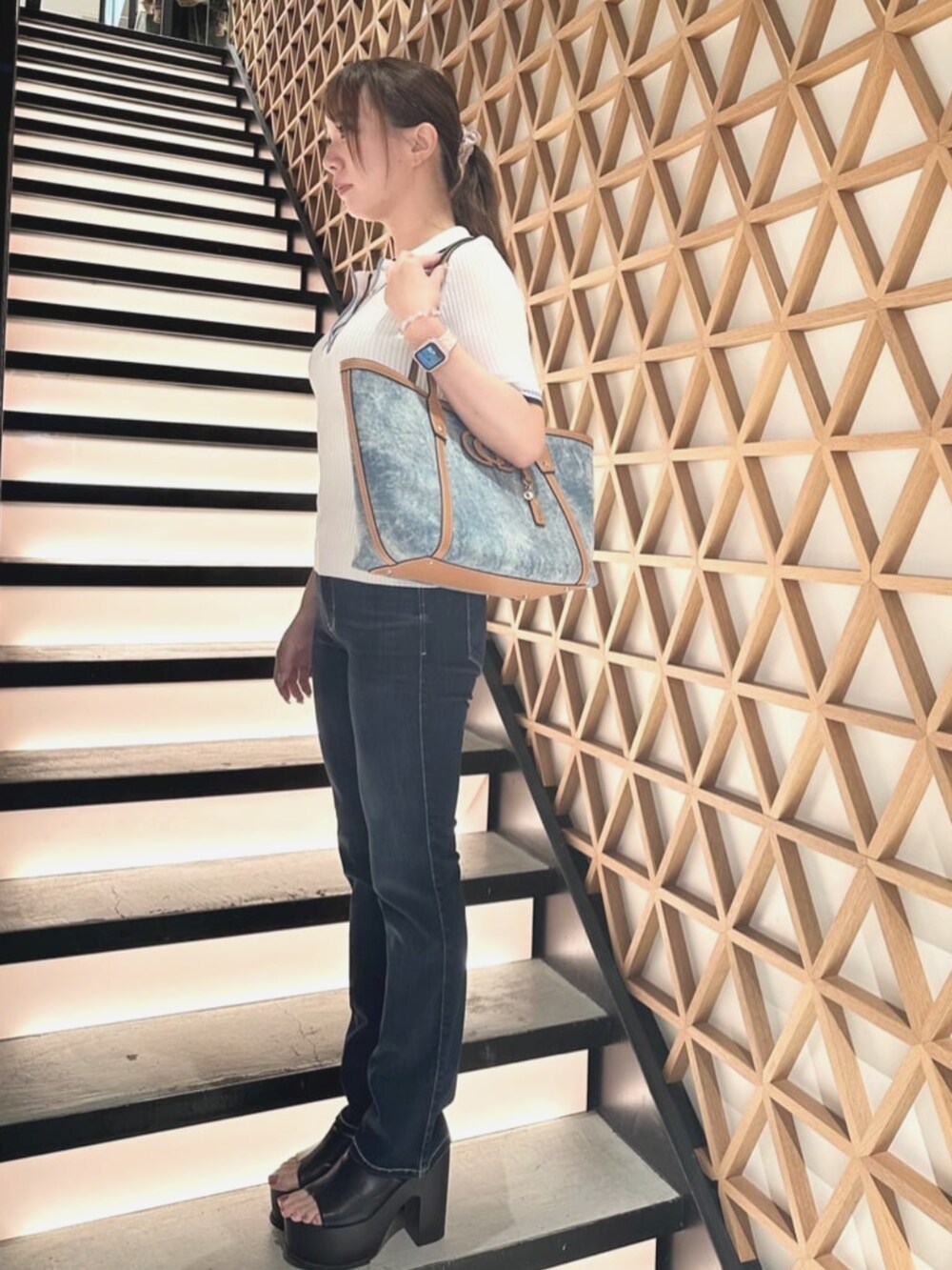 ブルー系のトートバッグ、ブルー系のデニムパンツ、ベージュ系のポロシャツを着用したレディースの夏コーディネートの3枚目の写真
