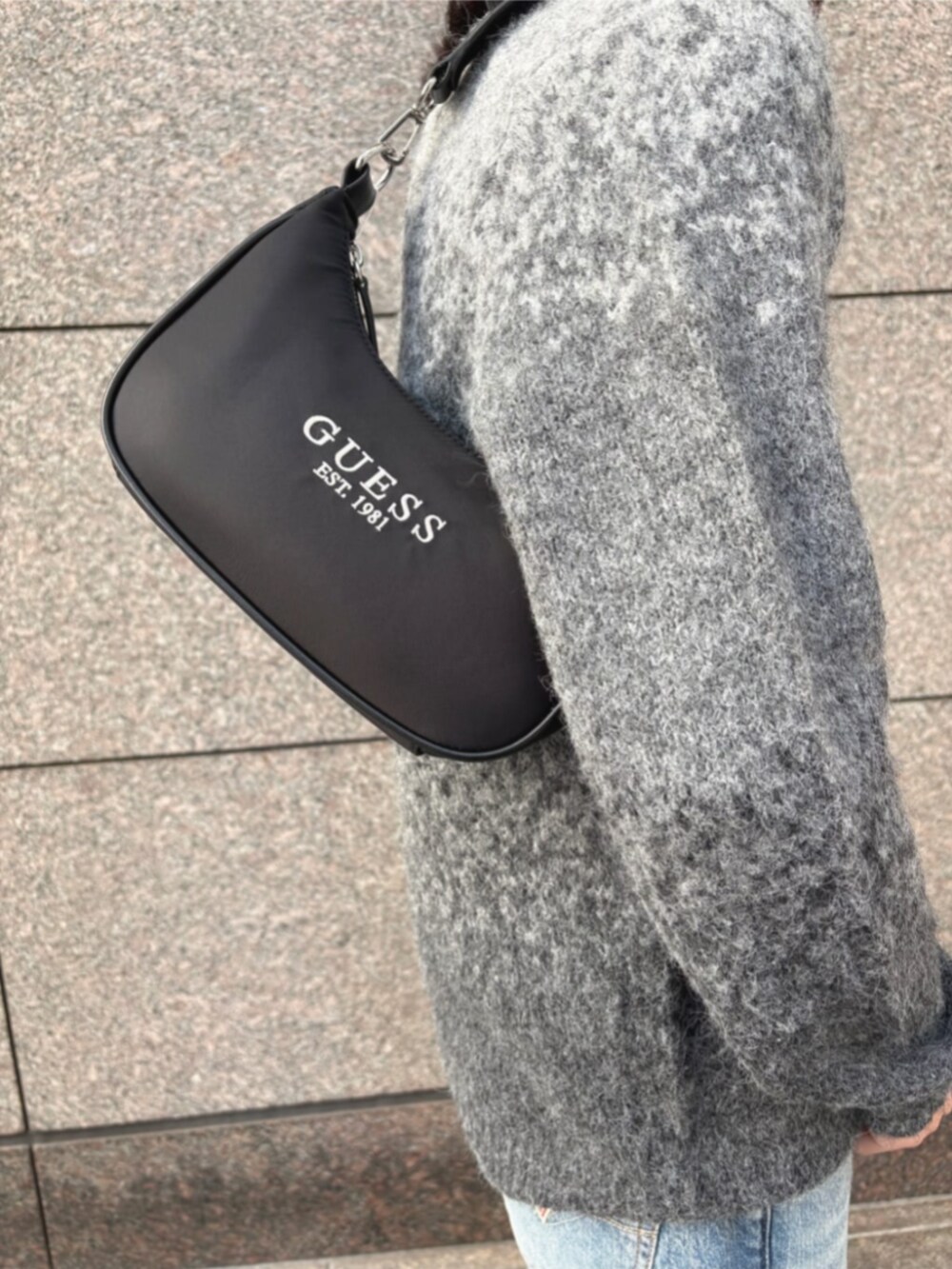 ブルー系のデニムパンツ、ブラック系のショルダーバッグ、グレー系のニット/セーターを着用したメンズの冬コーディネートの4枚目の写真