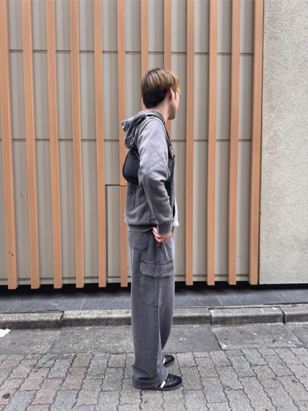 グレー系のパーカー、ブラック系のショルダーバッグを着用したメンズの秋コーディネートの4枚目の写真