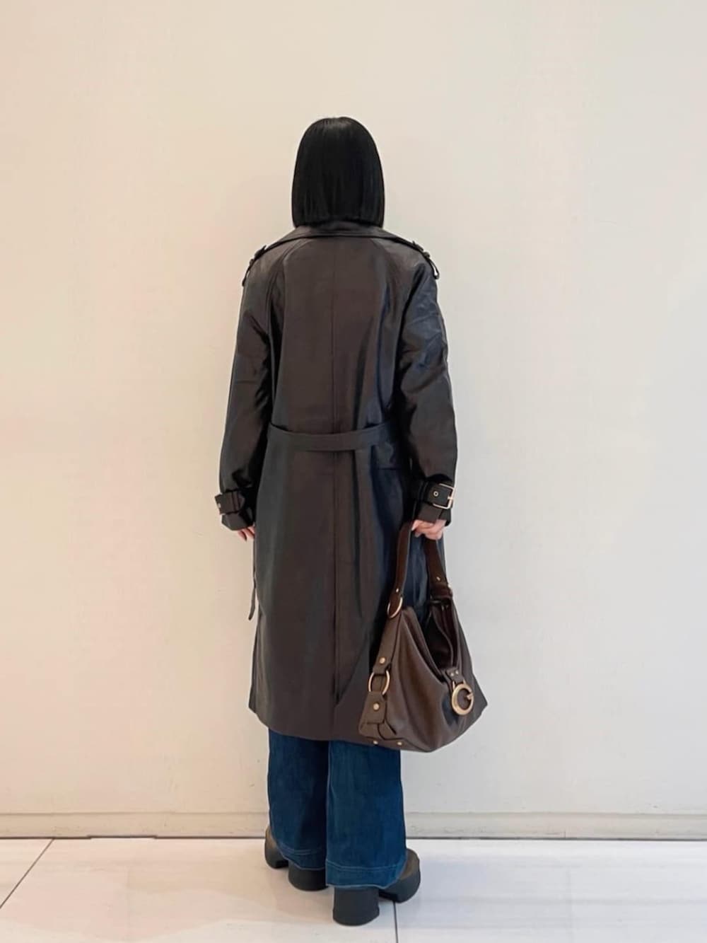 ブルー系のデニムパンツ、ブラウン系のショルダーバッグ、ブラウン系のトレンチコートを着用したレディースの春コーディネートの4枚目の写真