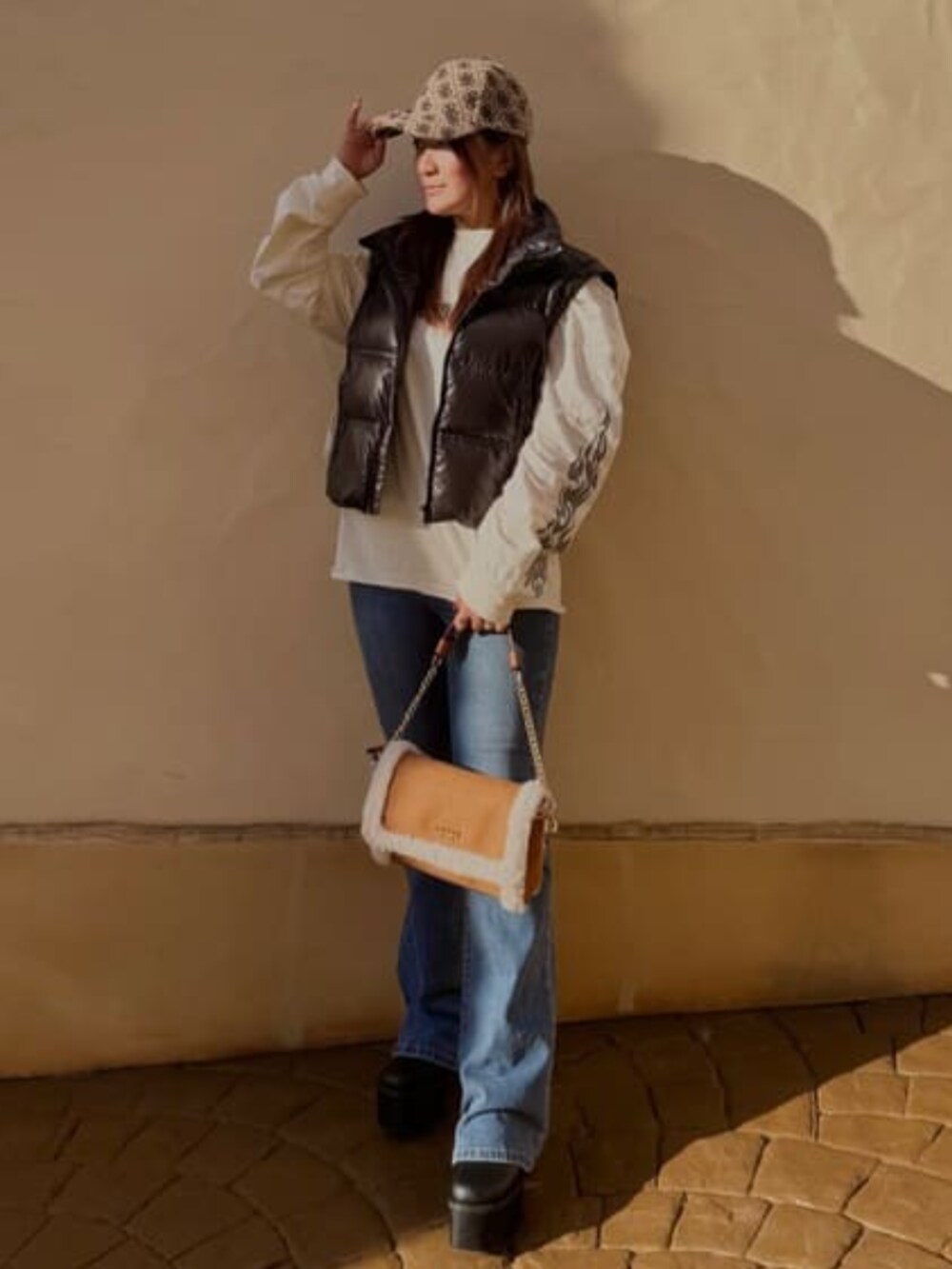 ブルー系のデニムパンツ、ブラウン系のショルダーバッグ、ブラック系のダウンジャケット/コートを着用したレディースの冬コーディネートの2枚目の写真