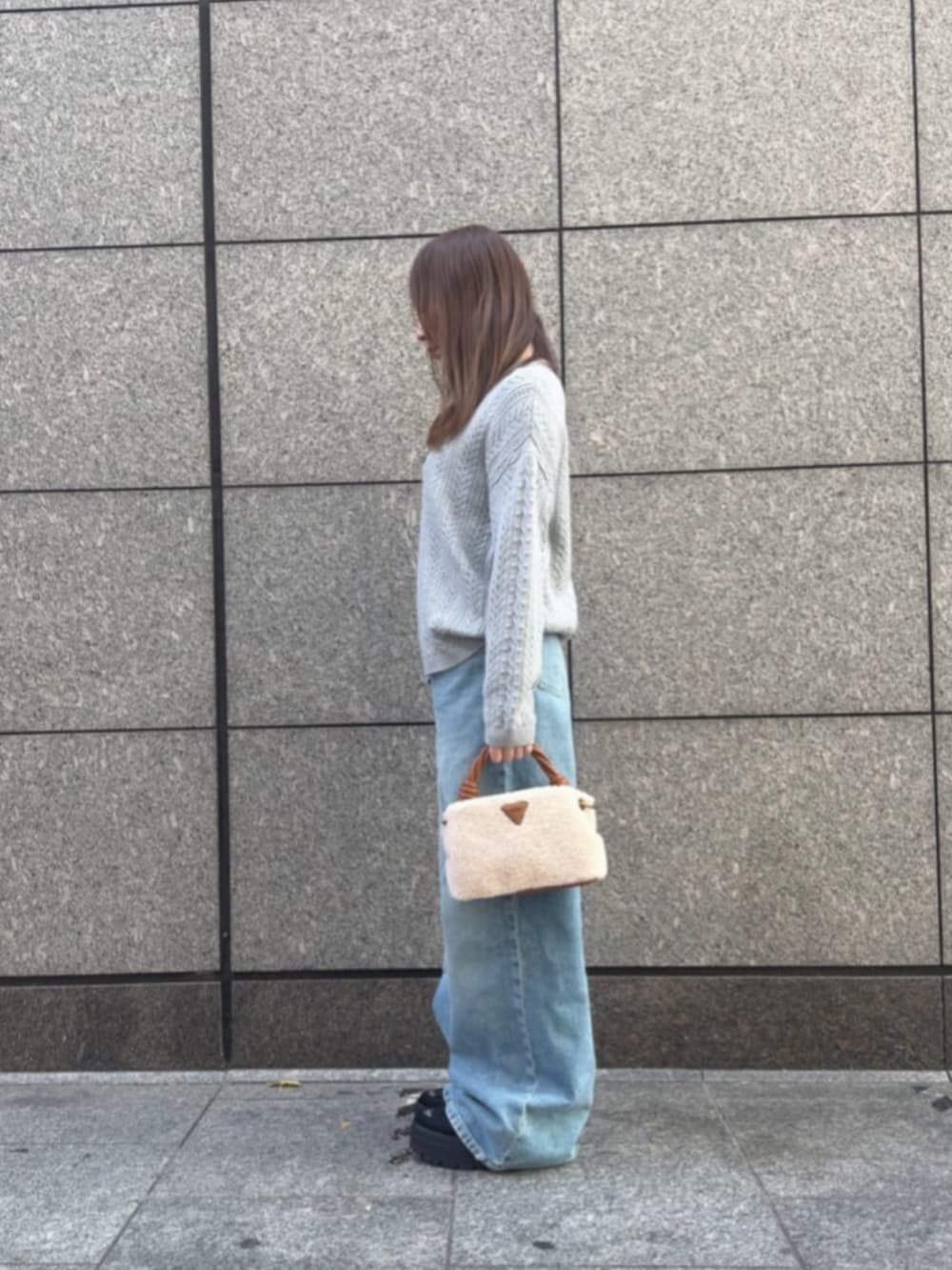 イエロー系のショルダーバッグ、グレー系のニット/セーター、ブルー系のデニムパンツを着用したレディースの冬コーディネートの3枚目の写真