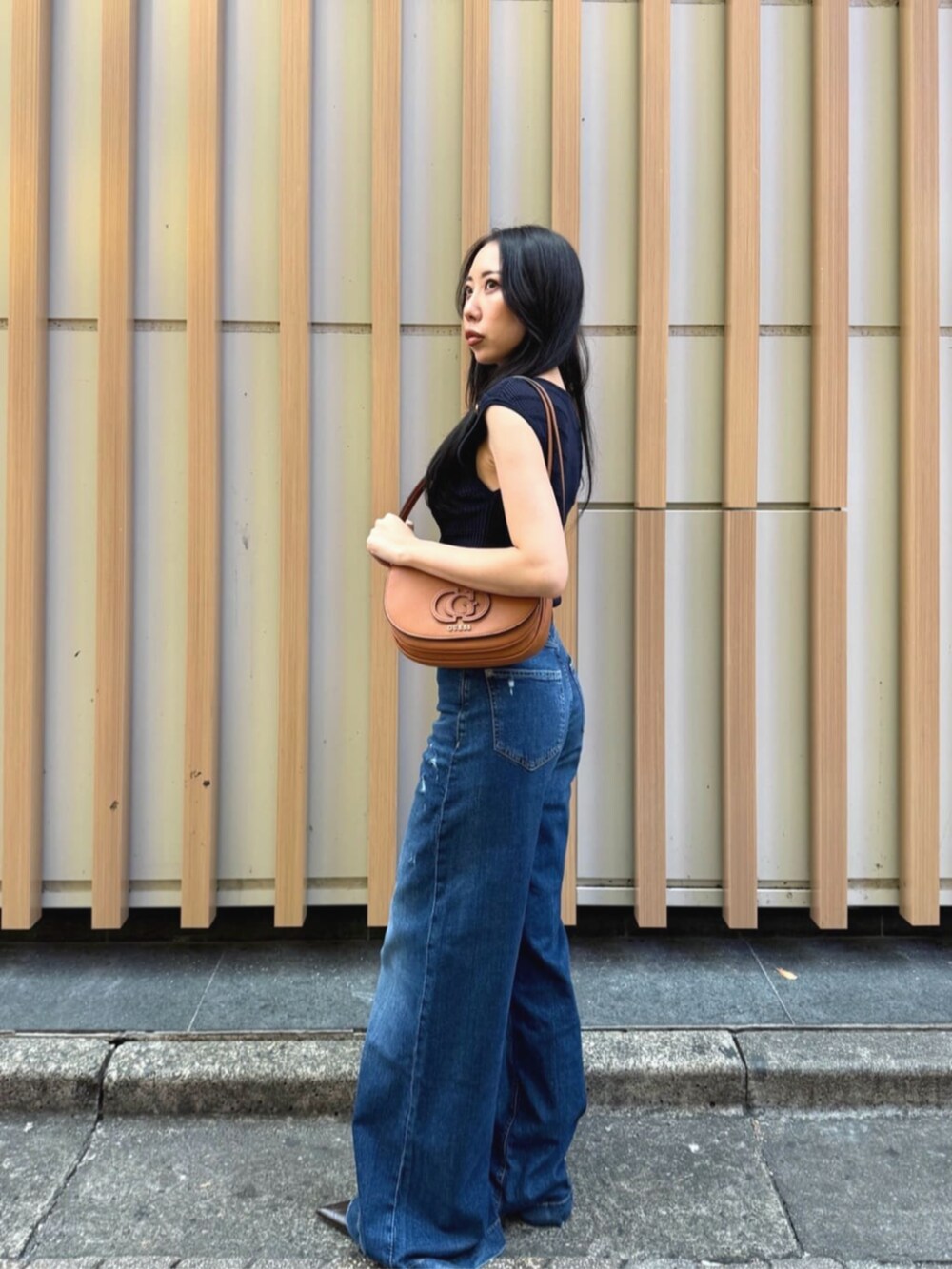 ブルー系のデニムパンツ、ブルー系のタンクトップ、ブラウン系のショルダーバッグを着用したレディースの秋コーディネートの3枚目の写真