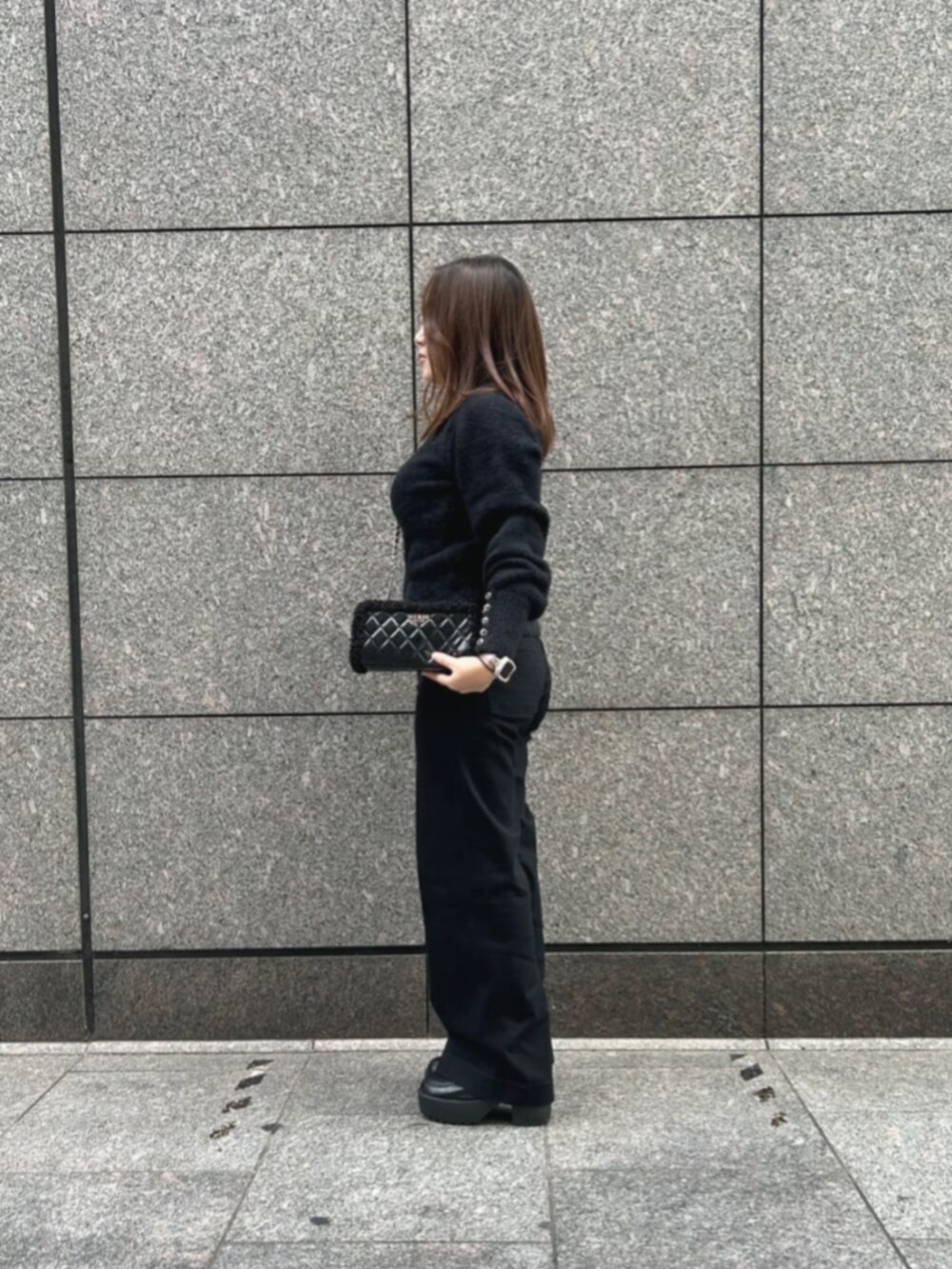 ブラック系のデニムパンツ、ブラック系のニット/セーター、ブラック系のショルダーバッグを着用したレディースの冬コーディネートの3枚目の写真