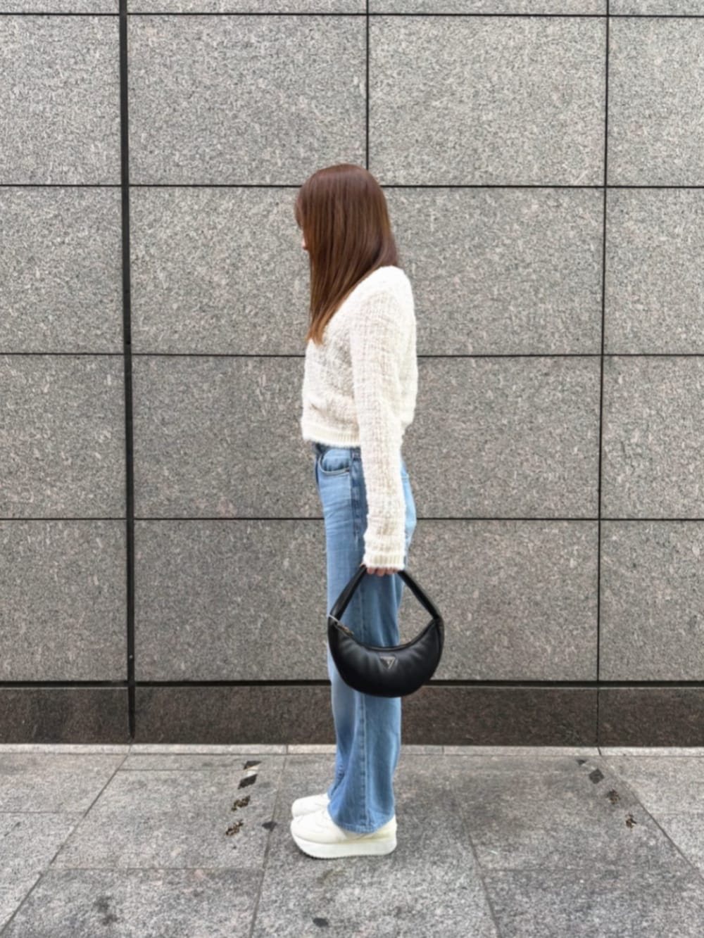 ブルー系のデニムパンツ、ブラック系のショルダーバッグ、ホワイト系のカーディガン/ボレロを着用したレディースの冬コーディネートの3枚目の写真