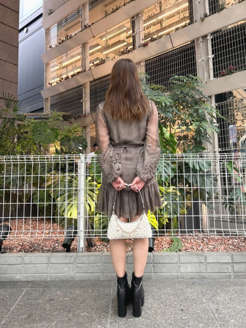 ホワイト系のハンドバッグ、ブラウン系のワンピースを着用したレディースの秋コーディネートの2枚目の写真