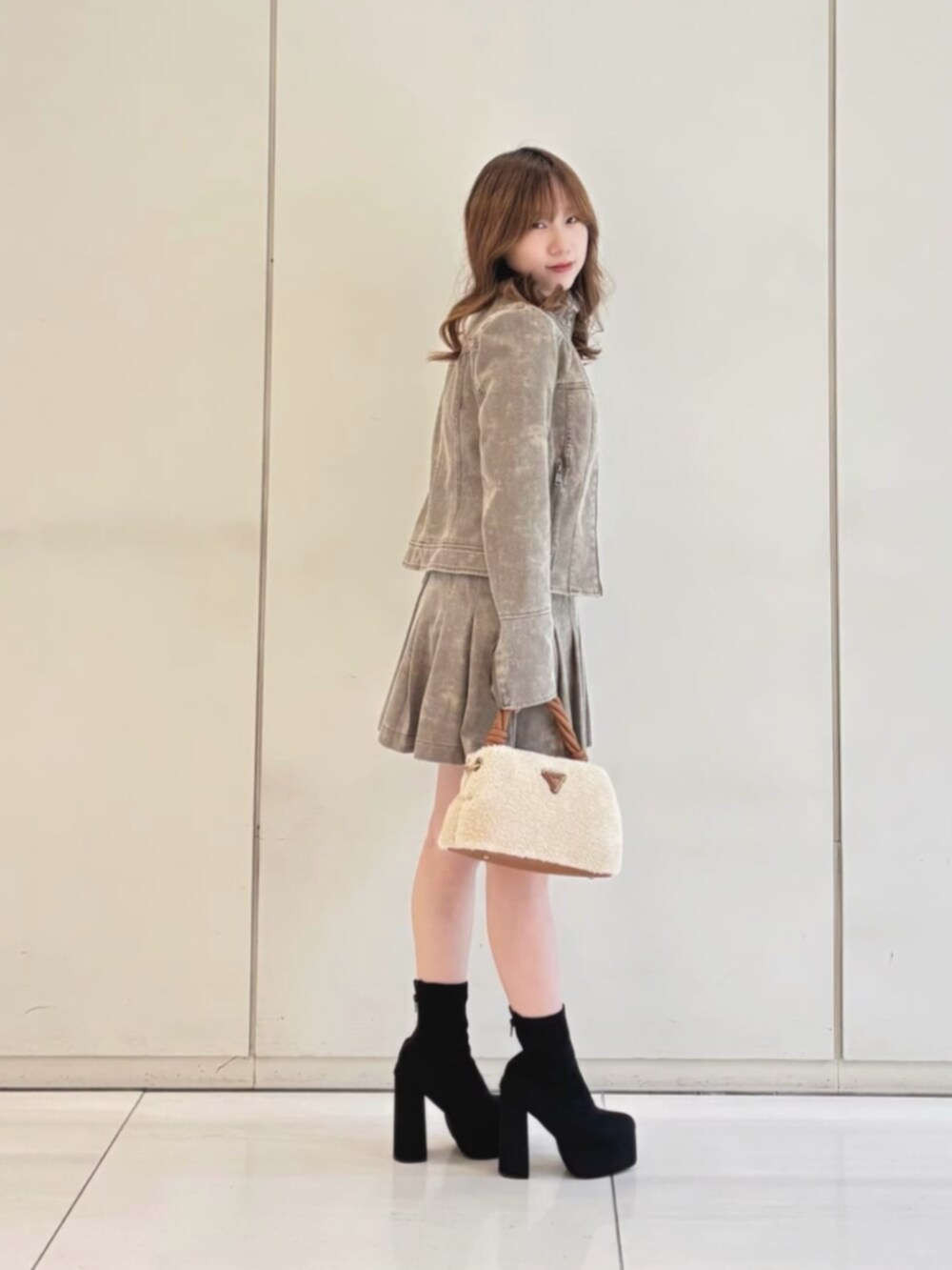 ベージュ系のスカート、ベージュ系のノーカラージャケット、イエロー系のショルダーバッグを着用したレディースの冬コーディネートの3枚目の写真