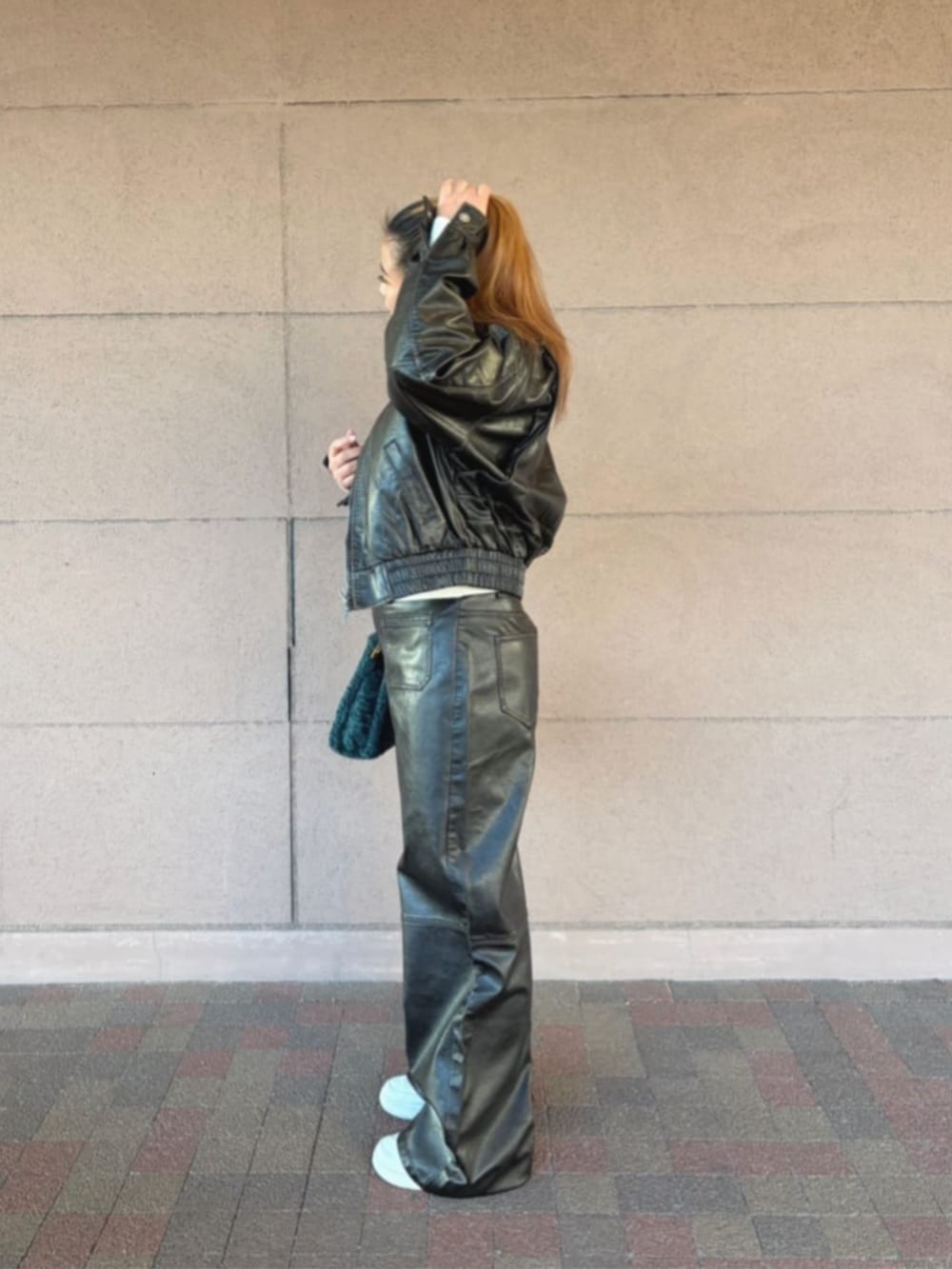 グリーン系のショルダーバッグ、ブラック系のその他アウター、ホワイト系のニット/セーターを着用したレディースの冬コーディネートの3枚目の写真