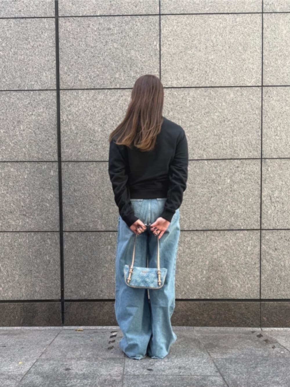 ブルー系のショルダーバッグ、ブラック系のスウェット、ブルー系のデニムパンツを着用したレディースの冬コーディネートの2枚目の写真