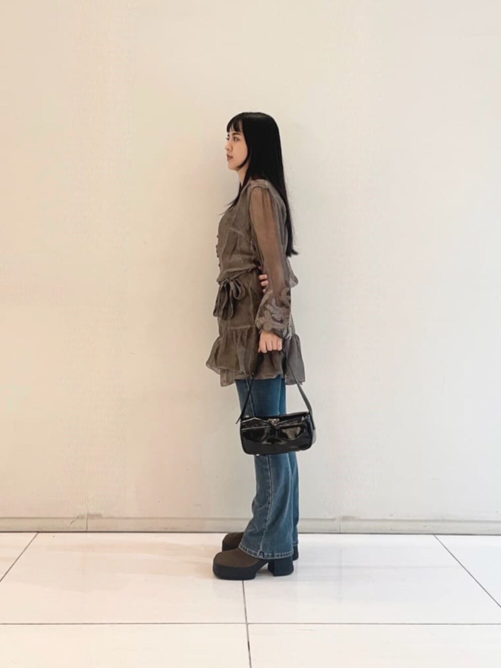 ブルー系のデニムパンツ、ブラック系のタンクトップ、ブラック系のショルダーバッグを着用したレディースの秋コーディネートの3枚目の写真