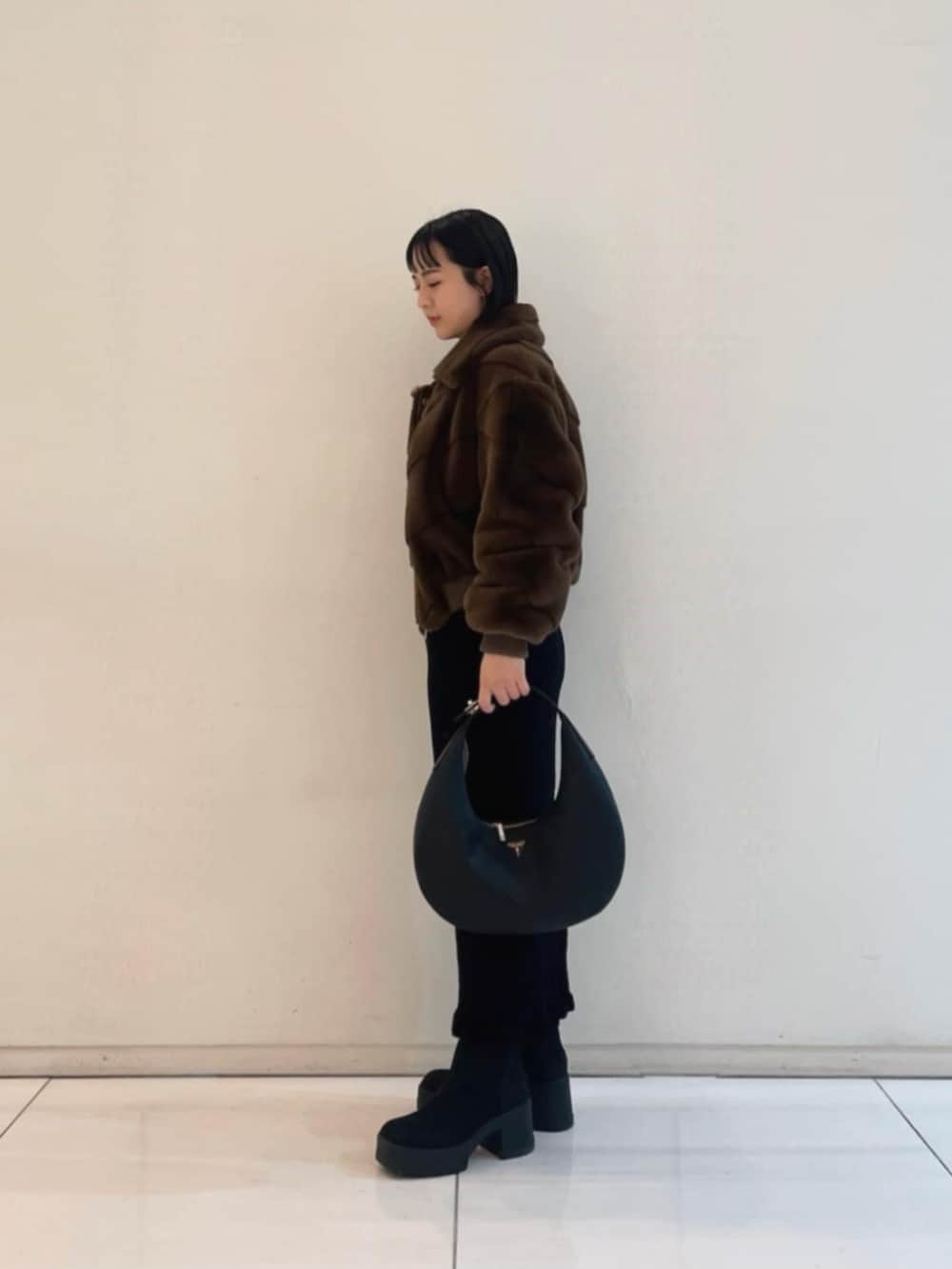 ブラック系のワンピース、ブラウン系のブルゾン、ブラック系のハンドバッグを着用したレディースの冬コーディネートの3枚目の写真