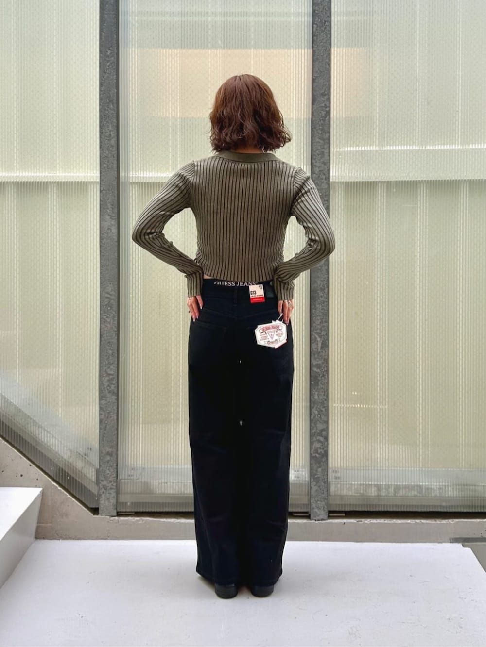 ブラック系のデニムパンツ、グリーン系のカーディガン/ボレロ、ブラック系のボクサーパンツを着用したレディースの秋コーディネートの2枚目の写真