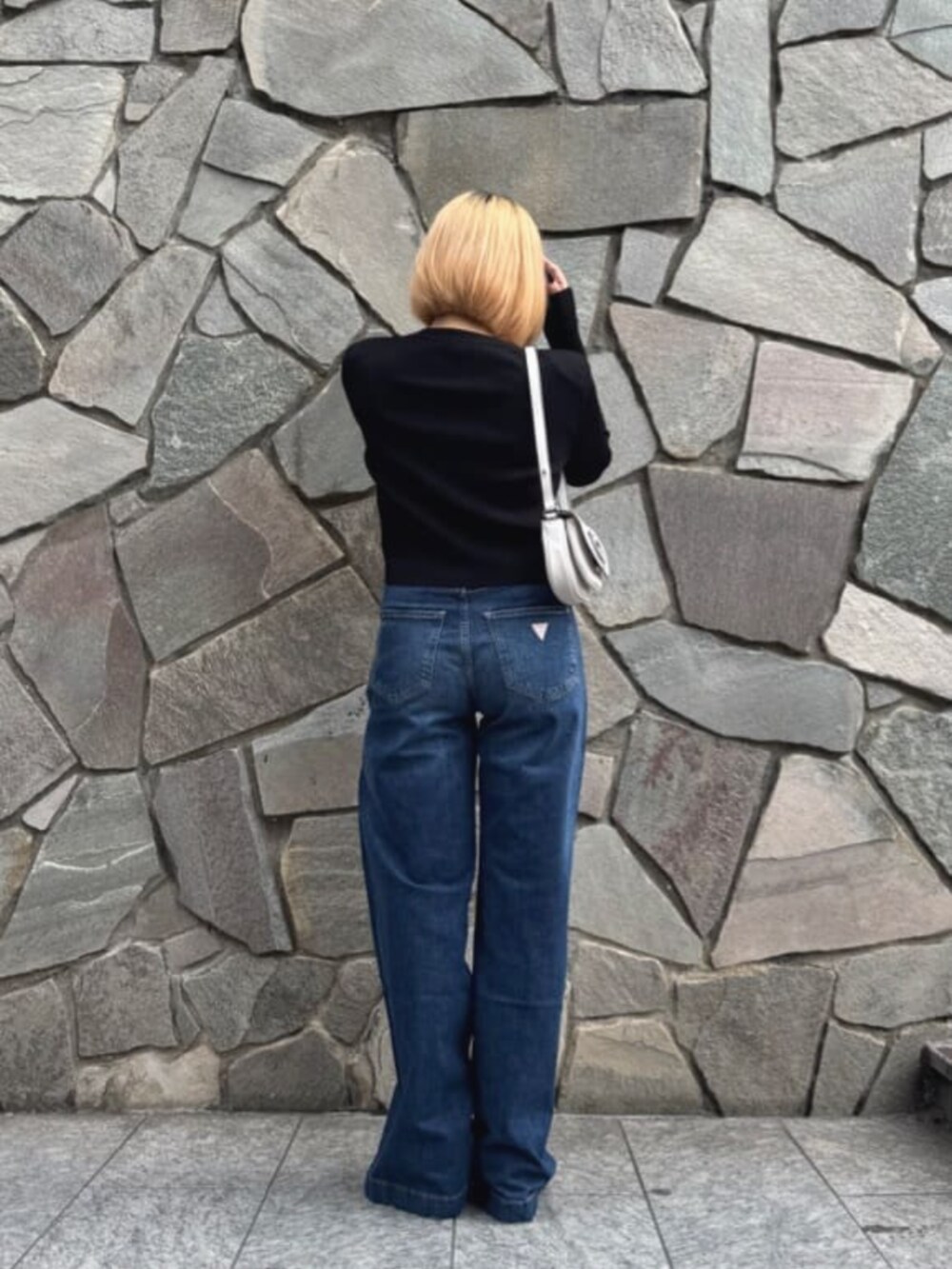 ホワイト系のショルダーバッグ、ベージュ系のカーディガン/ボレロ、ブルー系のデニムパンツを着用したレディースの秋コーディネートの2枚目の写真