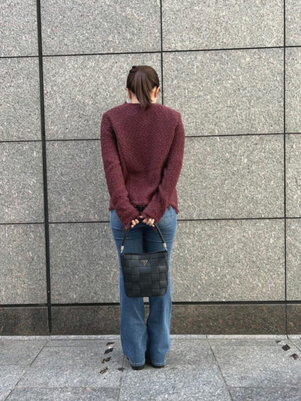 ブルー系のデニムパンツ、レッド系のノーカラージャケット、ブラック系のショルダーバッグを着用したレディースの秋コーディネートの2枚目の写真