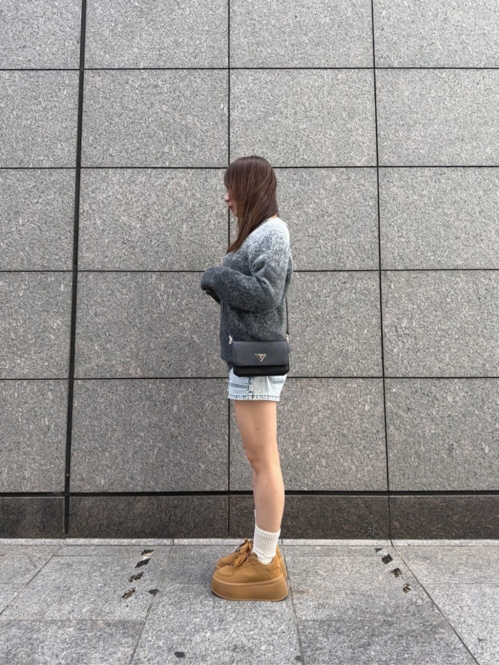 ブラック系のショルダーバッグ、ブルー系のデニムパンツ、グレー系のニット/セーターを着用したレディースの秋コーディネートの3枚目の写真