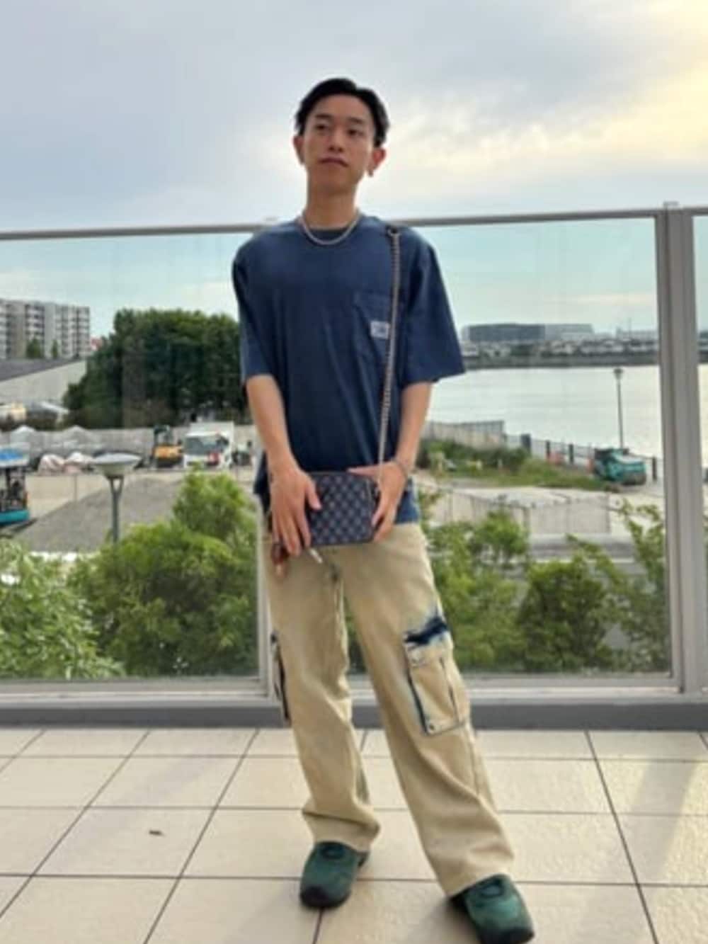 イエロー系のカーゴパンツ、ブルー系のショルダーバッグ、ブルー系のTシャツ/カットソーを着用したメンズの夏コーディネートの4枚目の写真