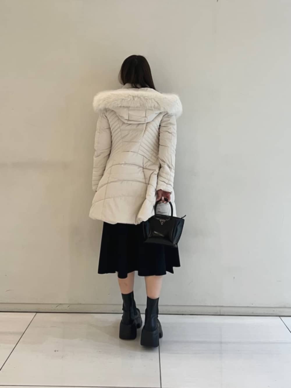 ブラック系のワンピース、ホワイト系のダウンジャケット/コート、ブラック系のトートバッグを着用したレディースの冬コーディネートの2枚目の写真