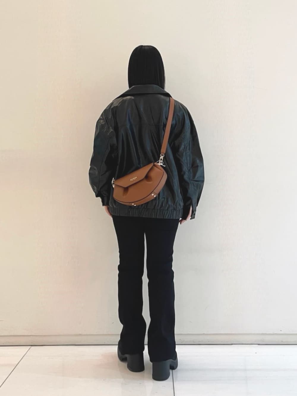 ブラック系のニット/セーター、ブラウン系のショルダーバッグ、ブラック系のカバーオールを着用したレディースの春コーディネートの3枚目の写真