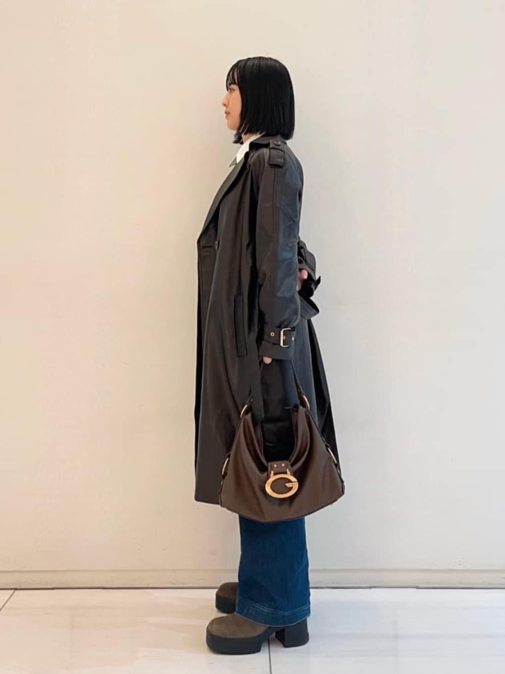 ブルー系のデニムパンツ、ブラウン系のショルダーバッグ、ブラウン系のトレンチコートを着用したレディースの春コーディネートの3枚目の写真