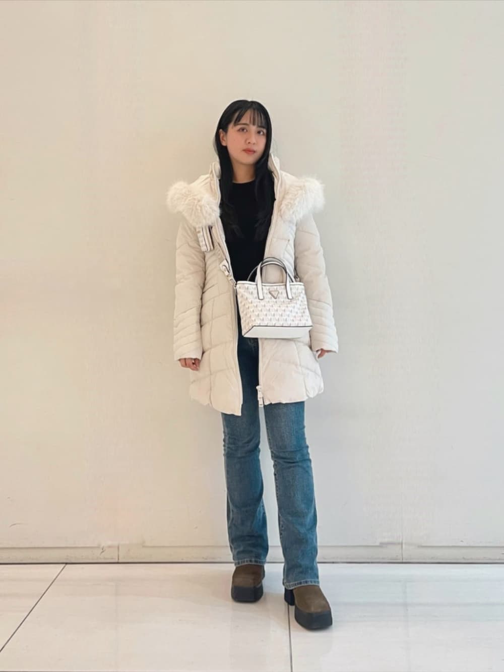 ブルー系のデニムパンツ、ブラック系のニット/セーター、ホワイト系のショルダーバッグを着用したレディースの秋コーディネートの4枚目の写真