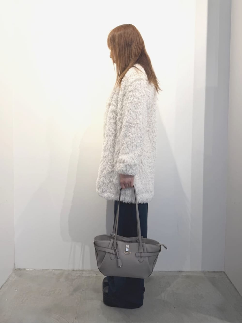 ホワイト系のカーディガン/ボレロ、ベージュ系のトートバッグ、ブルー系のデニムパンツを着用したレディースの春コーディネートの3枚目の写真