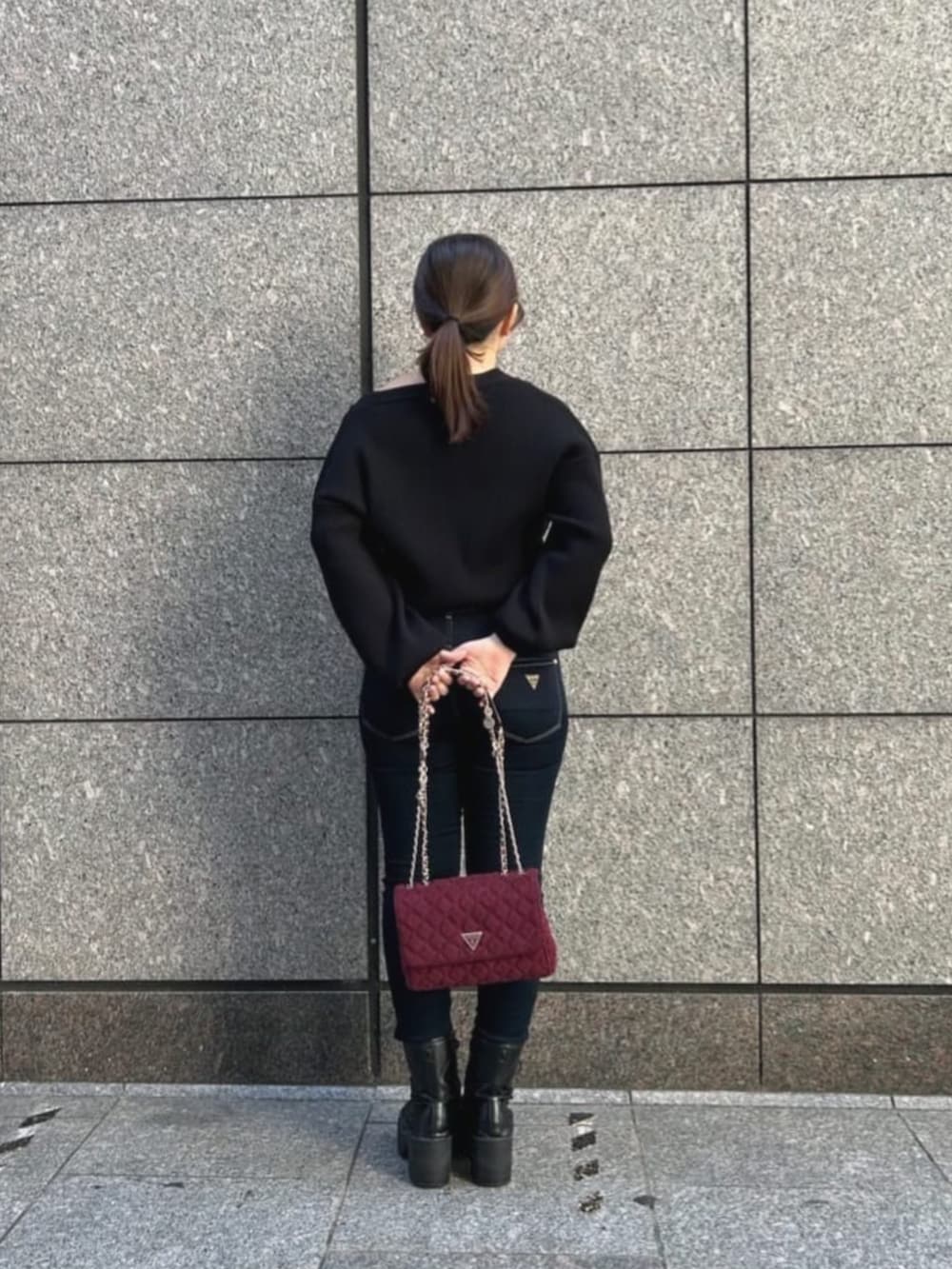 ブルー系のデニムパンツ、ブラック系のカーディガン/ボレロ、レッド系のショルダーバッグを着用したレディースの秋コーディネートの2枚目の写真