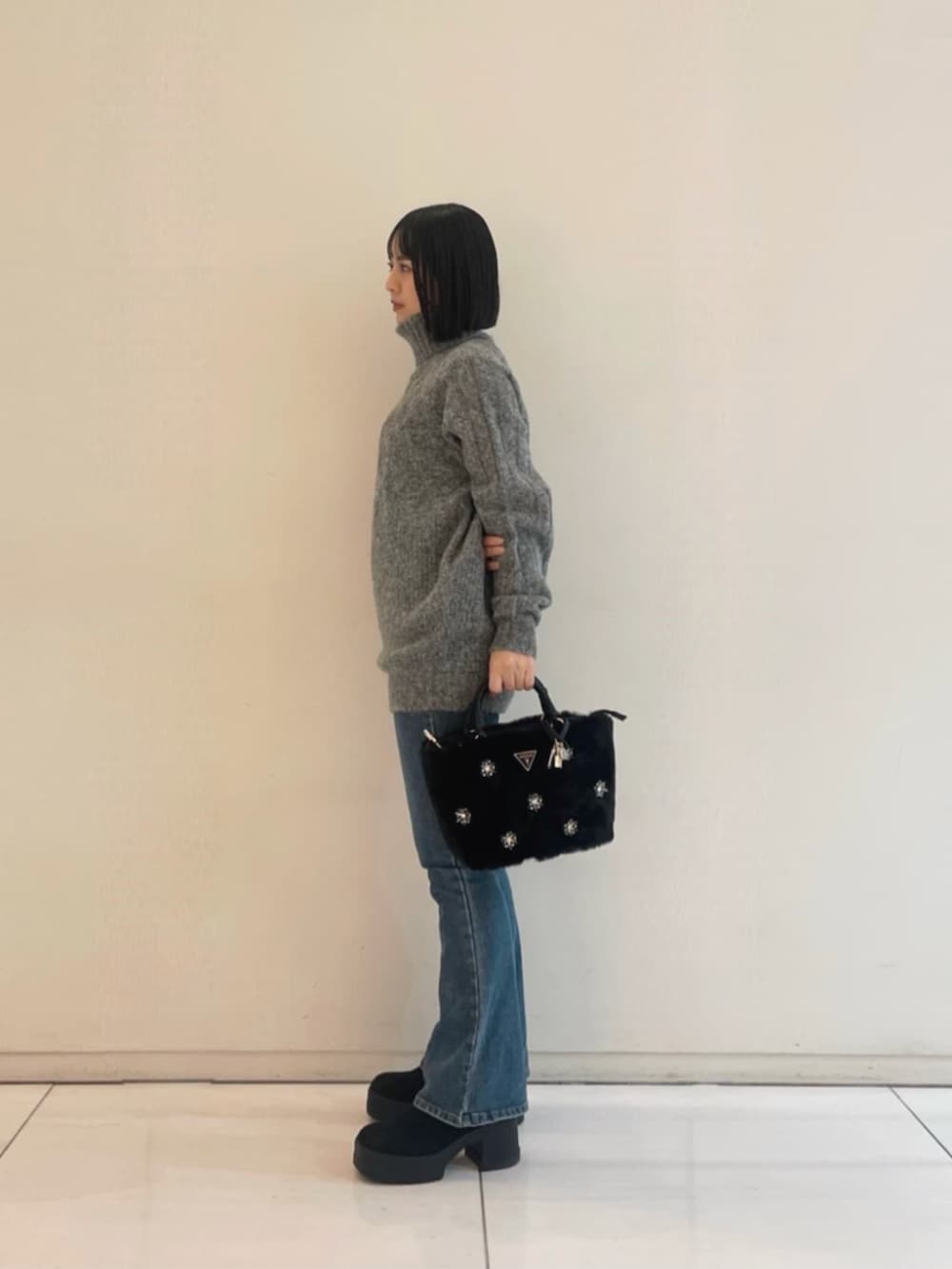 ブルー系のデニムパンツ、ブラック系のショルダーバッグ、グレー系のニット/セーターを着用したレディースの冬コーディネートの3枚目の写真