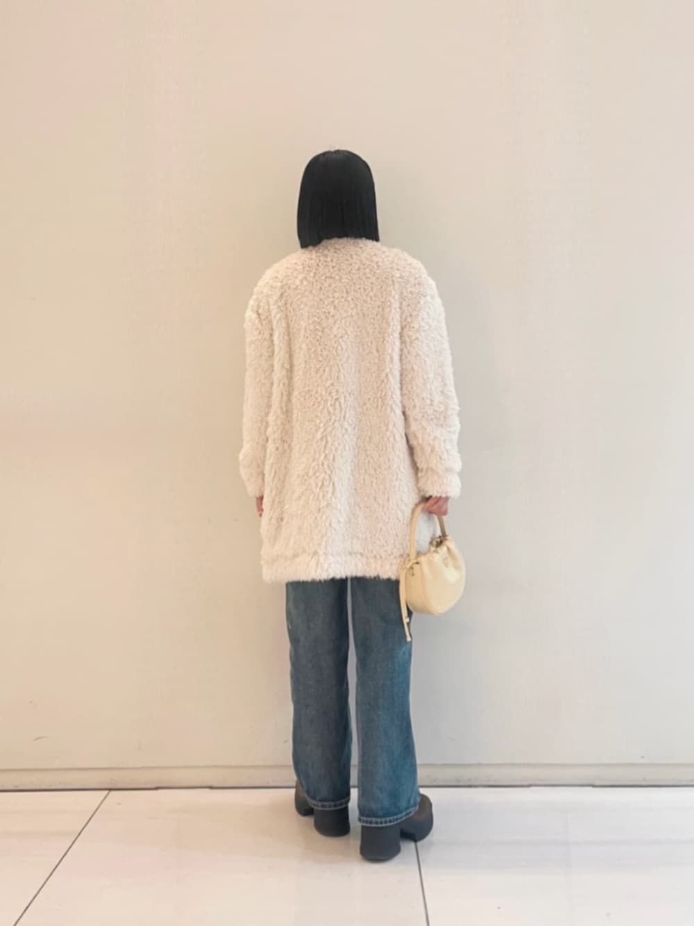 ブルー系のデニムパンツ、ホワイト系のカーディガン/ボレロ、ホワイト系のTシャツ/カットソーを着用したレディースの冬コーディネートの2枚目の写真