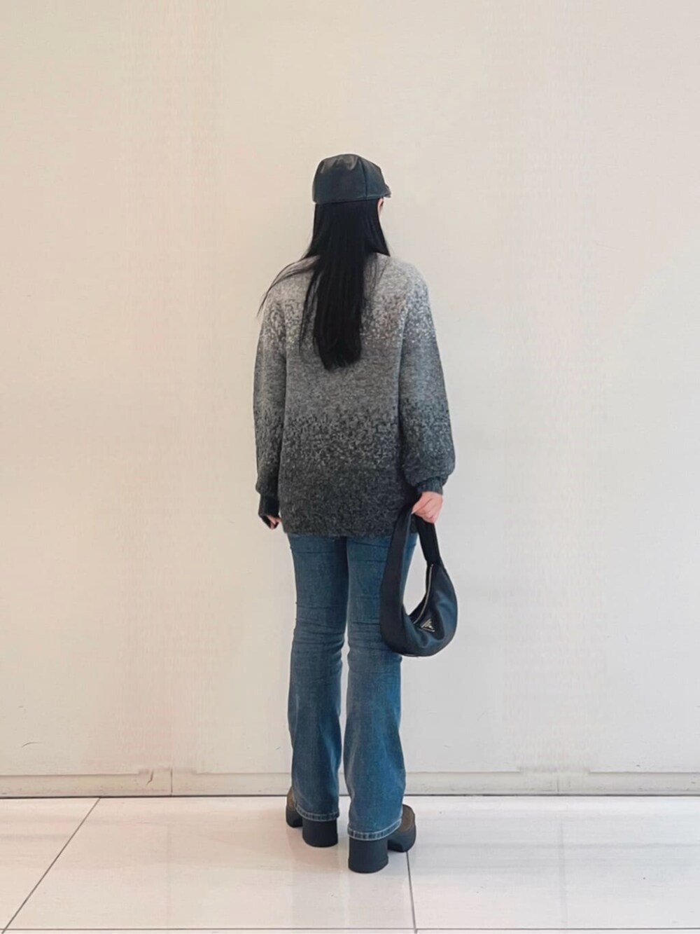 ブルー系のデニムパンツ、グレー系のニット/セーター、ブラック系のショルダーバッグを着用したレディースの秋コーディネートの2枚目の写真