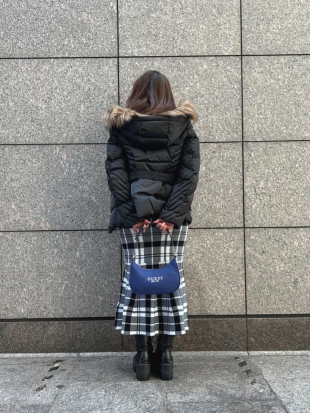 ブラック系のワンピース、ブルー系のショルダーバッグ、ブラック系のダウンジャケット/コートを着用したレディースの冬コーディネートの2枚目の写真