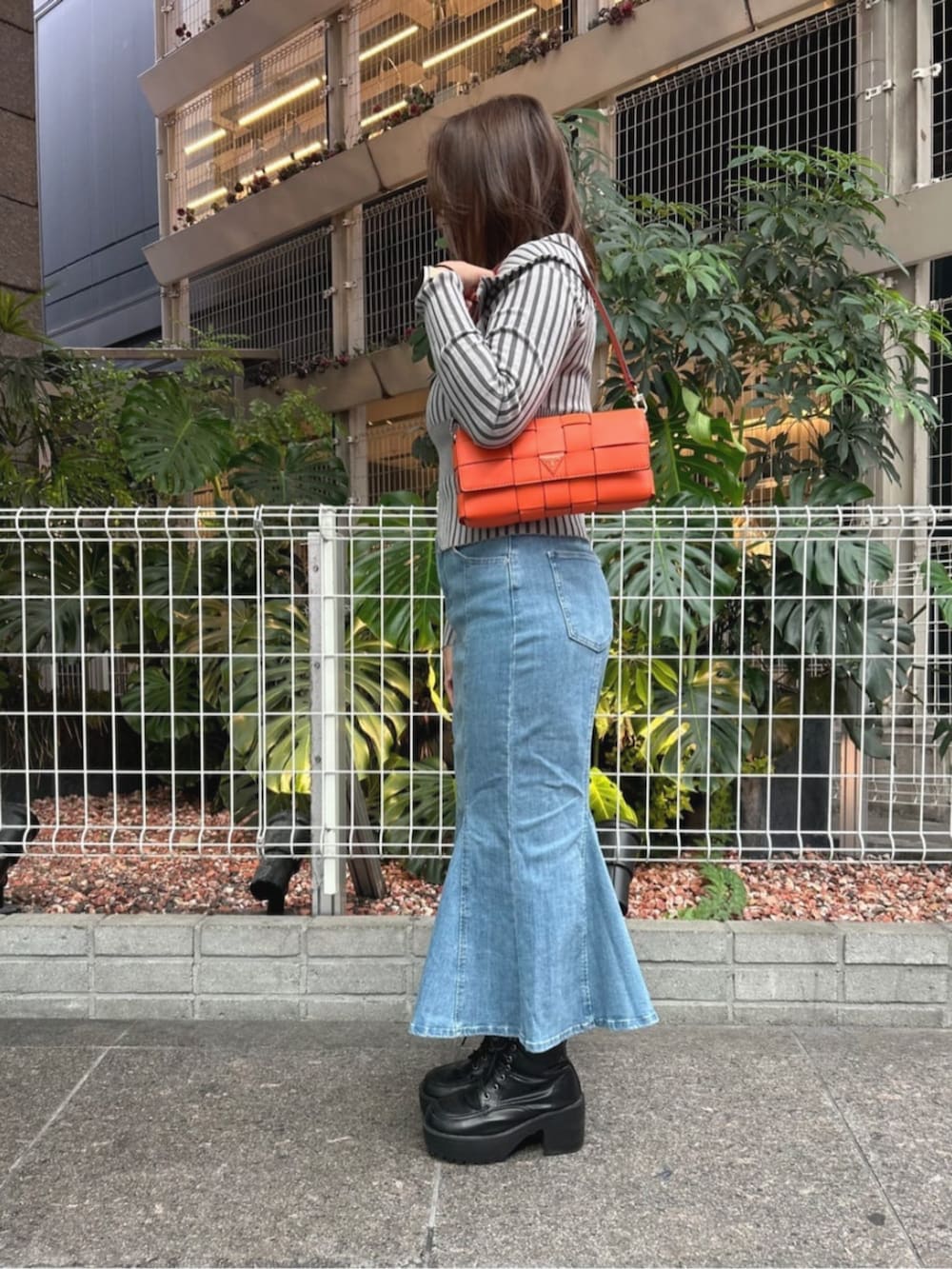 グレー系のカーディガン/ボレロ、ブルー系のデニムスカート、オレンジ系のショルダーバッグを着用したレディースの秋コーディネートの3枚目の写真