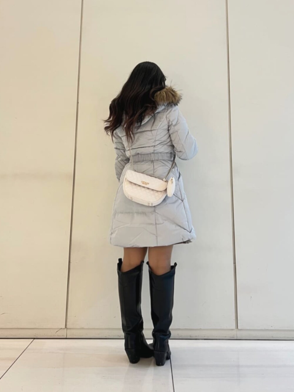 グレー系のダウンジャケット/コート、ベージュ系のワンピース、ホワイト系のショルダーバッグを着用したレディースの冬コーディネートの2枚目の写真
