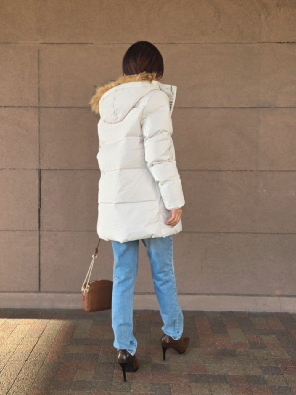 ブルー系のデニムパンツ、ブラック系のTシャツ/カットソー、ブラウン系のショルダーバッグを着用したレディースの冬コーディネートの2枚目の写真