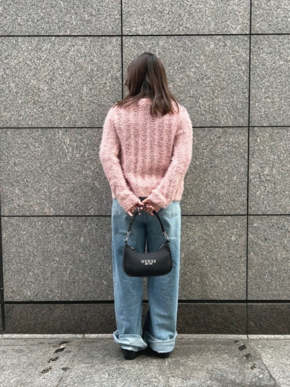 ブラック系のショルダーバッグ、ブルー系のデニムパンツ、ピンク系のカーディガン/ボレロを着用したレディースの冬コーディネートの2枚目の写真