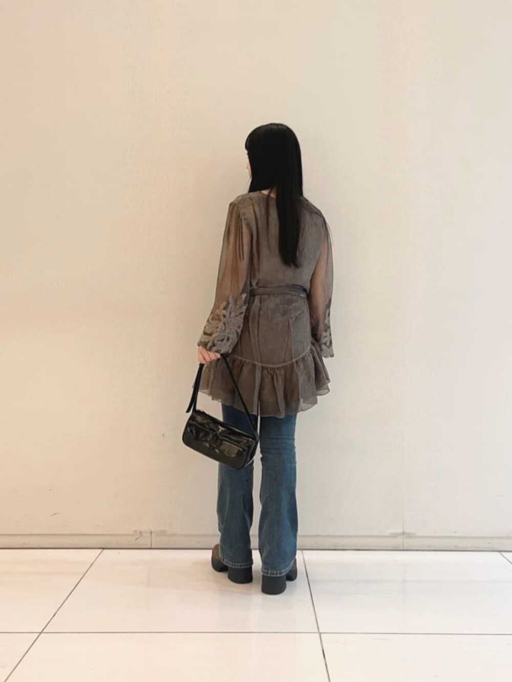 ブルー系のデニムパンツ、ブラック系のタンクトップ、ブラック系のショルダーバッグを着用したレディースの秋コーディネートの2枚目の写真