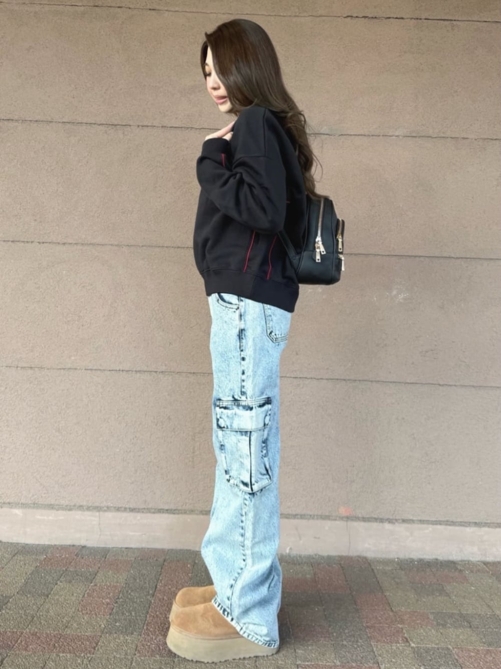 ブラック系のバックパック/リュック、ブルー系のデニムパンツ、ブラック系のスウェットを着用したレディースの冬コーディネートの3枚目の写真