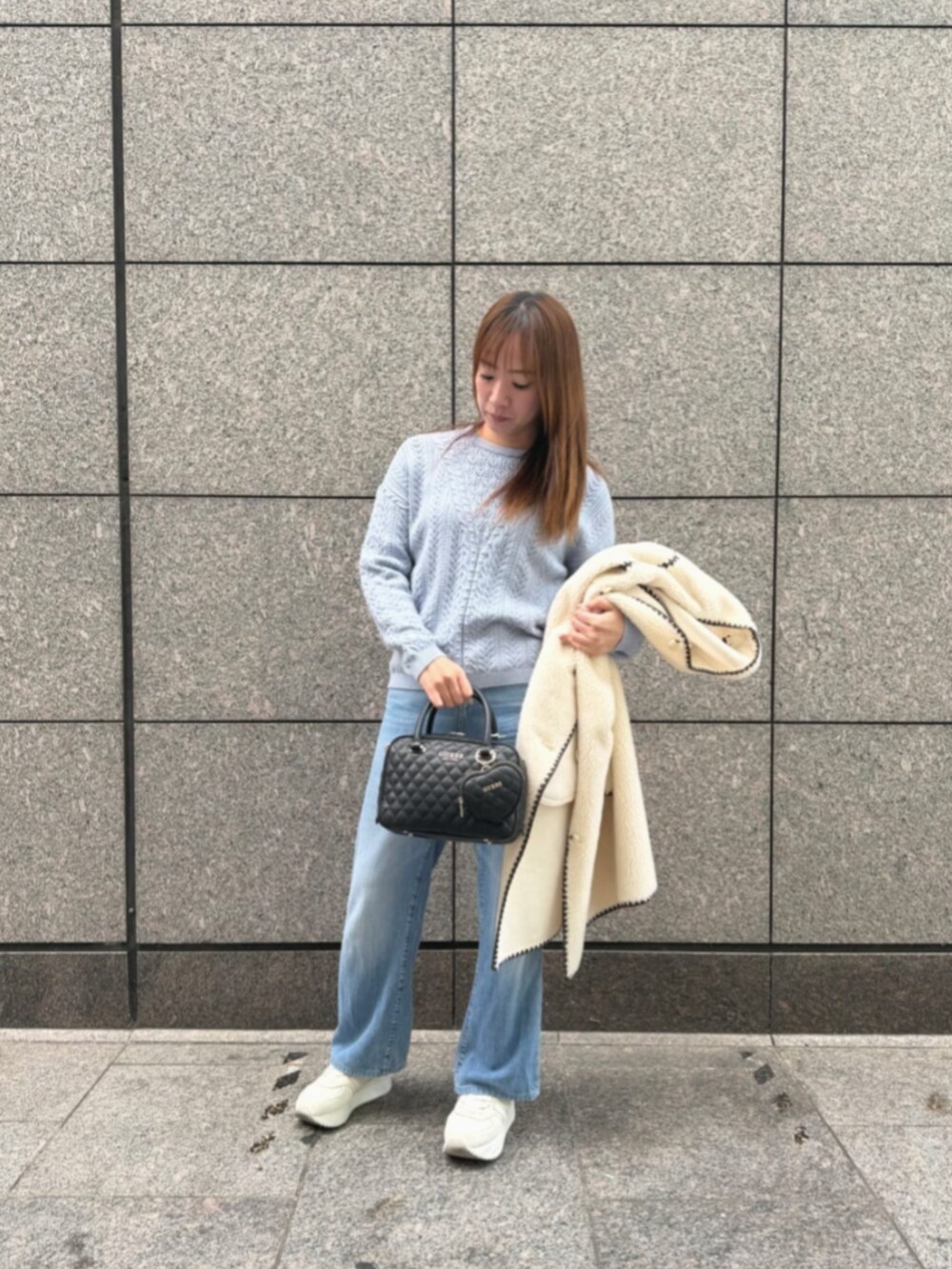 ブルー系のデニムパンツ、ブルー系のニット/セーター、ホワイト系のノーカラージャケットを着用したレディースの冬コーディネートの4枚目の写真