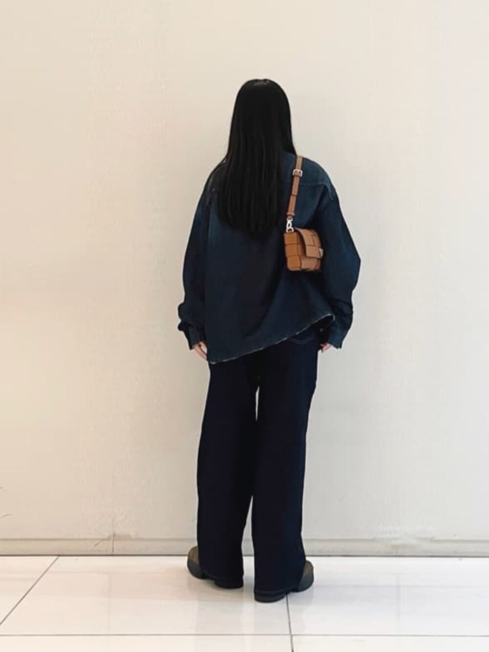 ブルー系のシャツ/ブラウス、イエロー系のショルダーバッグ、ブラック系のニット/セーターを着用したレディースの秋コーディネートの2枚目の写真