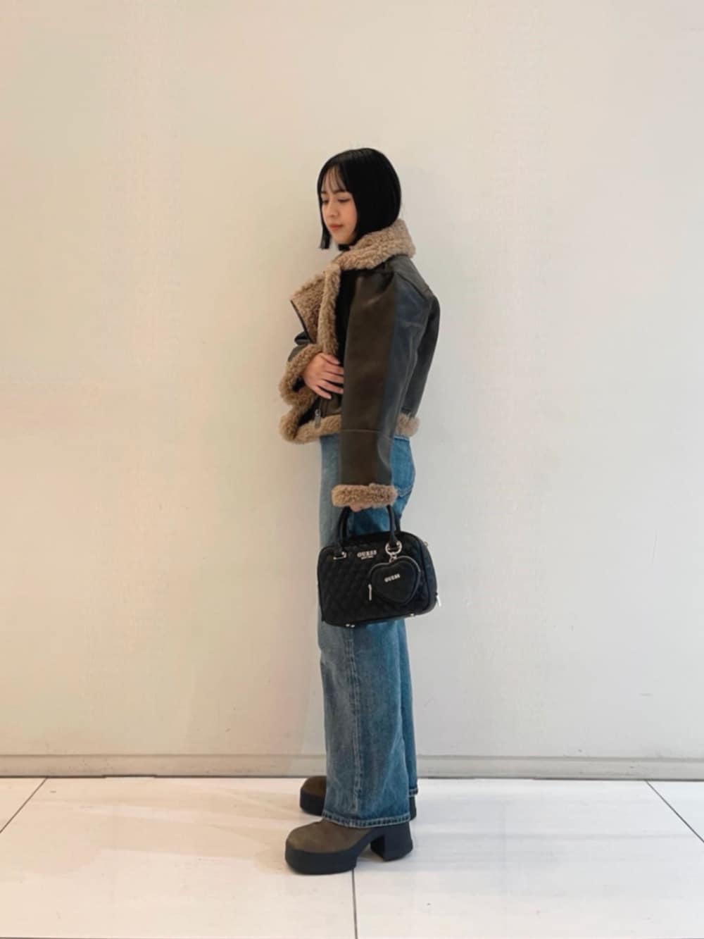 ブルー系のデニムパンツ、ブラック系のハンドバッグ、ブラック系のTシャツ/カットソーを着用したレディースの冬コーディネートの3枚目の写真