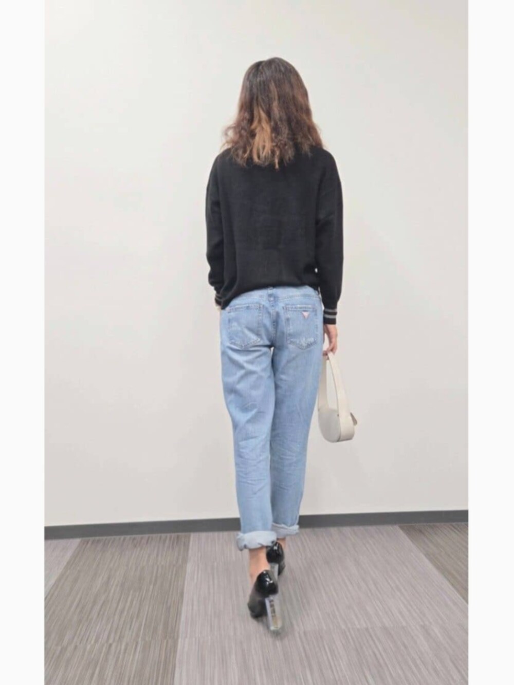 ブルー系のデニムパンツ、ブラック系のショルダーバッグ、ブラック系のニット/セーターを着用したレディースの冬コーディネートの2枚目の写真