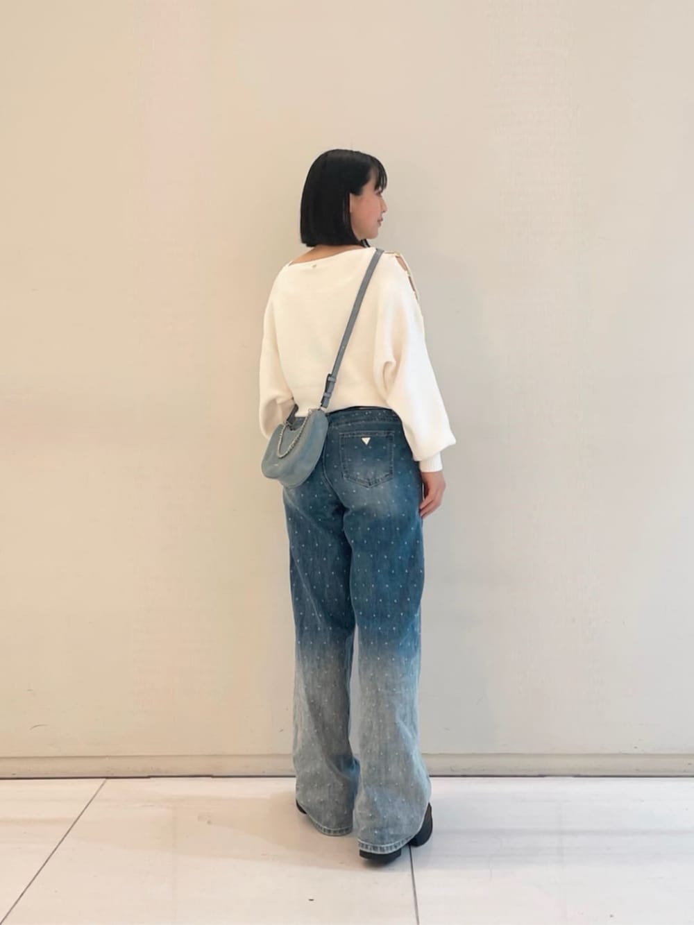 ブルー系のデニムパンツ、ホワイト系のニット/セーター、ベージュ系のタンクトップを着用したレディースの春コーディネートの2枚目の写真